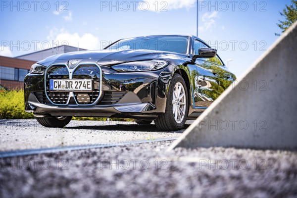 A black car presents itself under a blue sky in a parking lot, BMW i7 electric car, Deer
