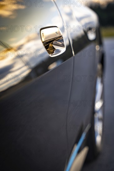 Close-up of a car door with sunset reflections on the paint, BMW i7 electric car, Deer