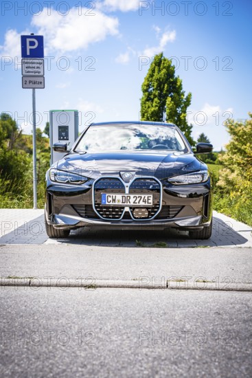 A black car is parked at a charging station with clear blue sky, BMW i7 electric car, Deer