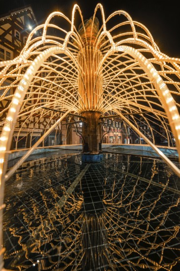 Artistic view of an illuminated fountain with detailed water reflections at night, Calw, Black