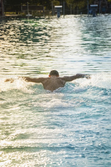 A swimmer swims in the pool, the afternoon sun reflecting on the water, Triathlon, Calw, Germany