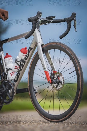 Front view of a racing bike with two water bottles standing on a country road under blue sky,