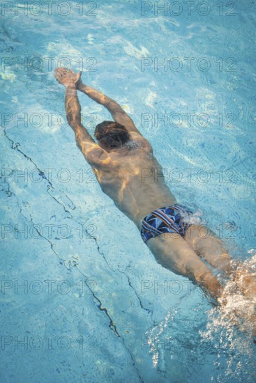 A diver in the pool shows dynamic underwater movements with splashing water, Triathlon, Calw,