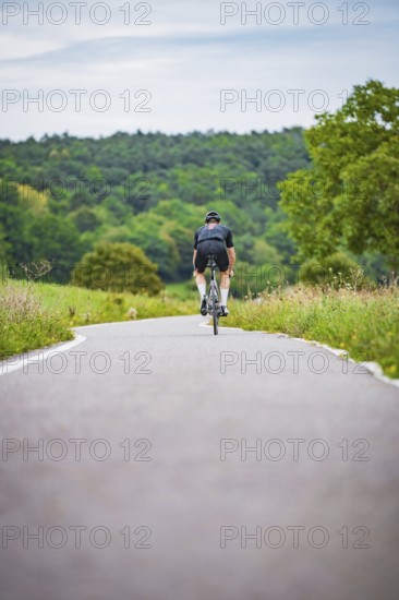 Cyclists in the distance on a winding country road surrounded by green countryside, Triathlon,