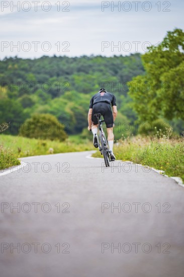 Cyclist climbing a road in hilly countryside surrounded by greenery, triathlon, Calw, Germany