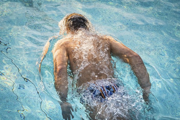 A swimmer in the pool shows energetic movements with strong splashes of water, Triathlon, Calw,