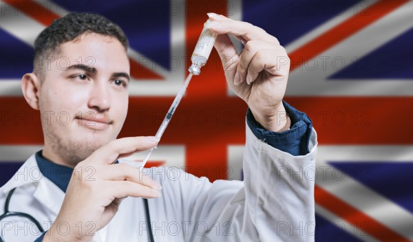 Doctor holding syringe on United Kingdom flag background. Medical professional holding syringe with