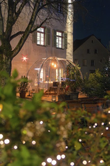An illuminated dome at night, surrounded by trees and decorative lighting, with windows in the