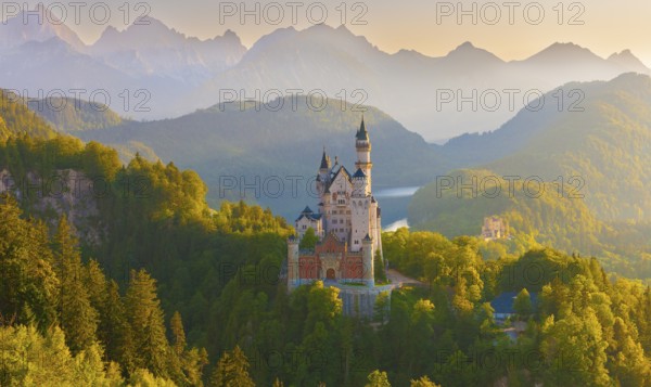 Neuschwanstein Castle in the midst of a fairytale alpine panorama during sunrise surrounded by