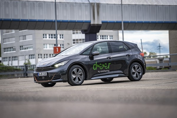 A modern Cupra stands in a parking lot in an urban area under a cloudy sky, electric car Cupra,
