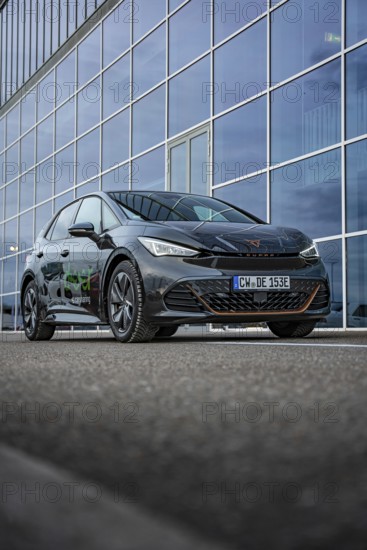 An elegant car depicted on asphalt in front of a glass façade, electric car Cupra, e-car sharing,