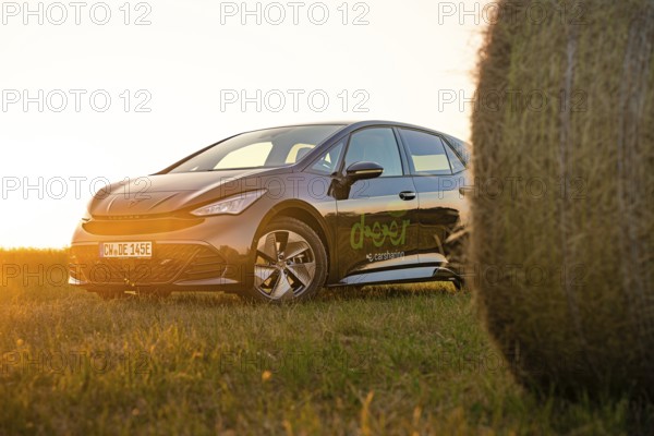 Car next to a hay bale in a rural landscape at sunset, electric car Cupra, e-car sharing, Calw,