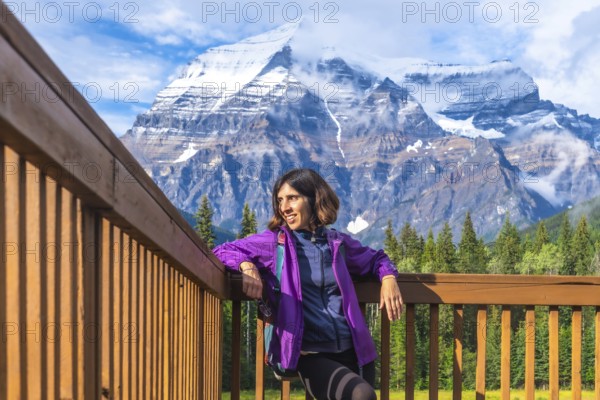Female hiker is taking a break and enjoying breathtaking view of mount robson, the highest peak in