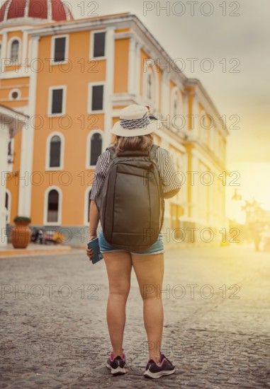 Travel woman in a tourist square at sunset, Granada, Nicaragua. Back view of tourist girl walking