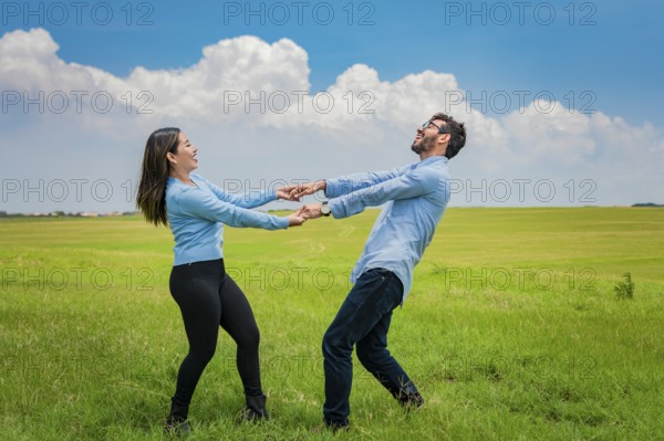 Happy couple spinning in a circle in the field, happy young couple spinning and playing in the