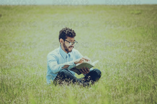 Young man on the grass reading a book, A person sitting on the grass reading a book, concept of