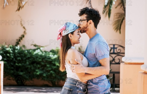 Cute couple embracing the boyfriend kisses the girl forehead. Portrait of beautiful couple in love.
