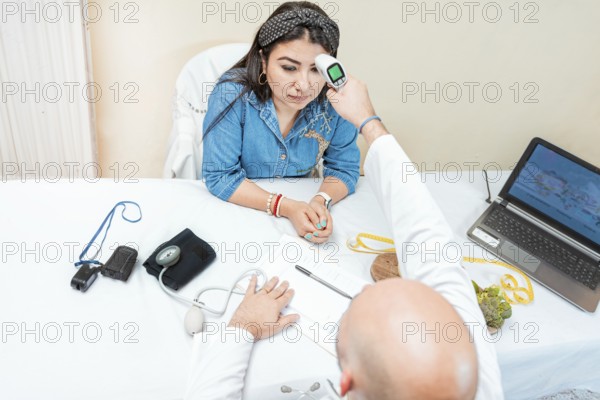 Male doctor taking temperature with gun to patient. Doctor measuring temperature with infrared gun