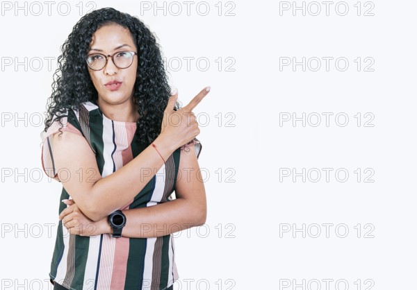 Beautiful afro young woman pointing an advertising to side. Surprised girl in glasses pointing to a