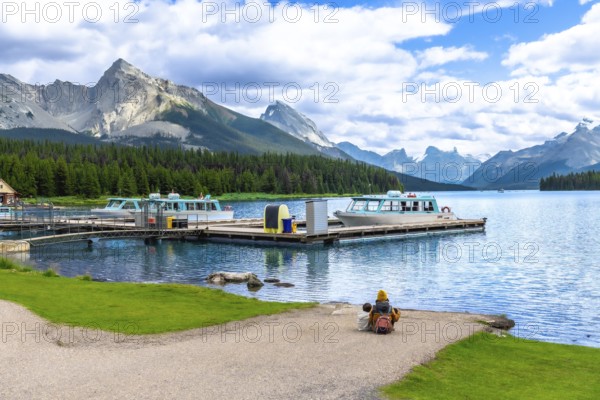 Tourists are enjoying the breathtaking view of maligne lake with tour boats and spirit island in