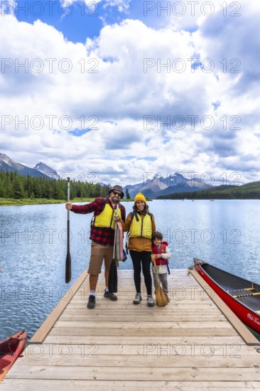 Family wearing life jackets standing on a wooden dock, ready for canoeing on maligne lake with the