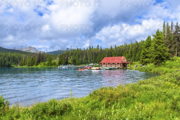 Beautiful summer landscape featuring a vibrant red roofed boathouse on the serene shores of maligne