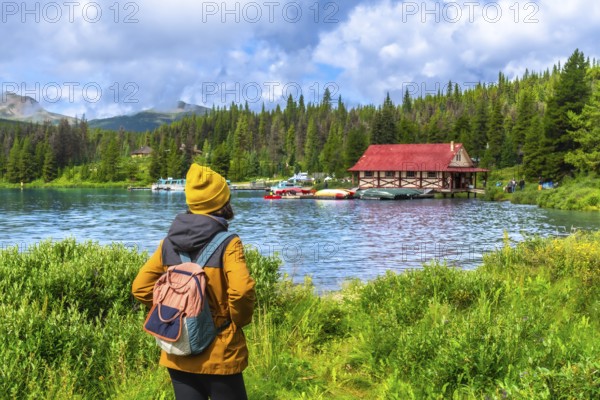 Female tourist wearing a yellow beanie and backpack enjoying the breathtaking view of maligne lake