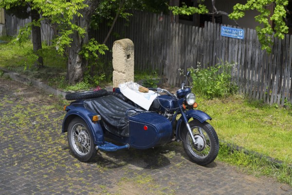 Blue motorcycle with sidecar parked on a cobblestone road, motorcycle team, model of the Ukrainian