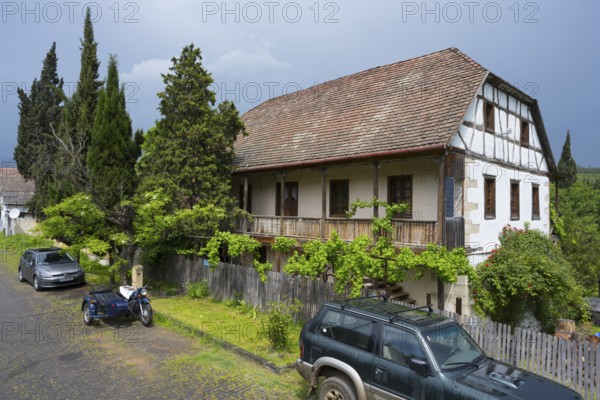 Half-timbered rural house with parked car and motorbike on a cobblestone street, Schwabenstraße 15,
