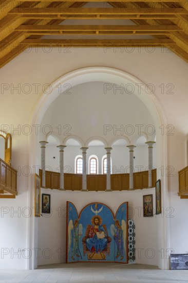 Church interior with icon wall under large white arches. Harmonious symmetry in space, German