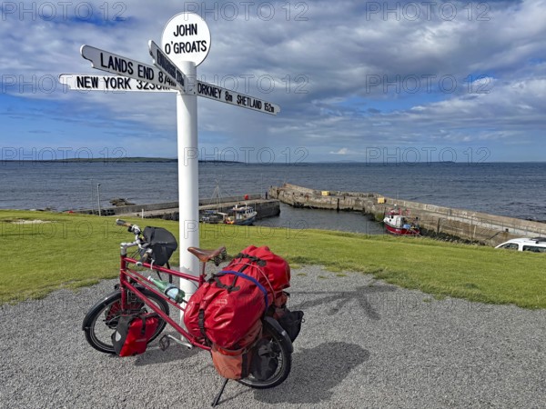 Packed bike in front of lake sign and harbor view in John O'Groats, bicycle trips, bicycle