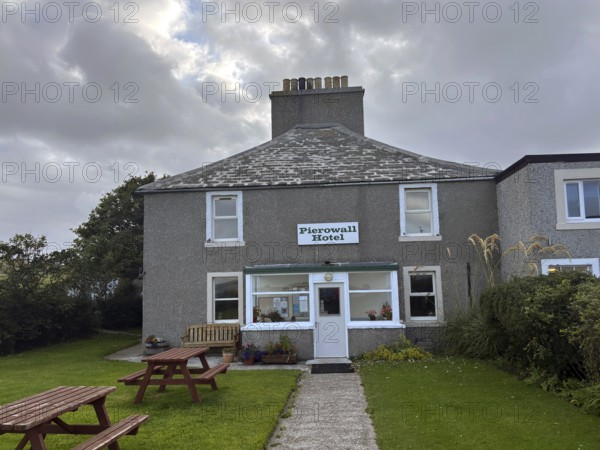Classic hotel view under cloudy sky with green surroundings and picnic tables, only hotel on