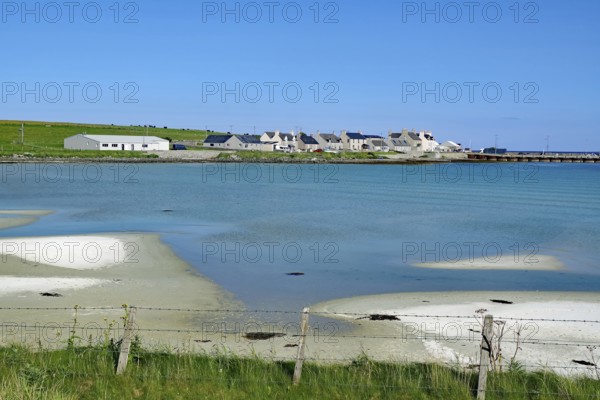 Small village on a peaceful coast with blue water and clear skies, Pierowall, Orkney Islands,
