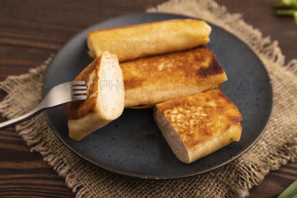 Fried crispy pancakes with meat and cheese on brown wooden background and linen textile. side view,