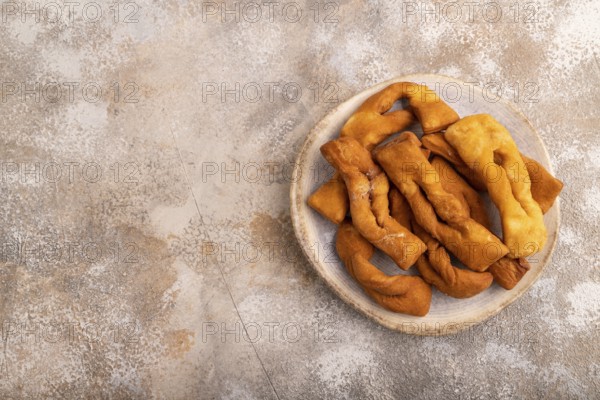 Crunchy biscuit Brushwood cookies sprinkled with powdered sugar on brown concrete background, top
