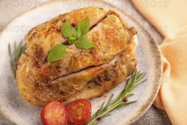 Fried Turkey Thigh with spices and rosemary on plate on brown concrete background and orange linen