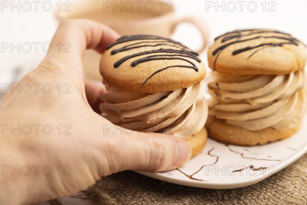 Caramel Cream Cakes with hand on white wooden background and linen textile, cup of coffee, side