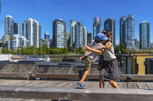 Mother and her son are sharing a tender hug on a wooden pier in vancouver's yaletown neighborhood,
