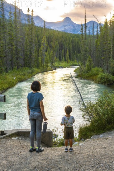 Mother and her son are enjoying the breathtaking view of a pristine river flowing through a lush