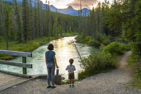 Mother and her son are enjoying a breathtaking sunset view over a pristine river flowing through