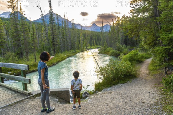 Woman points towards the majestic mountains in the distance as she and her son stand near a