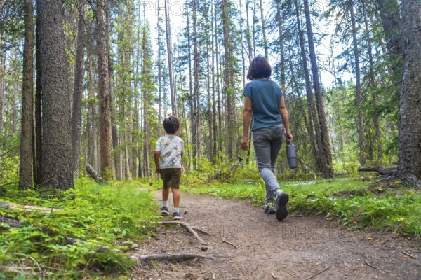 Mother and son enjoying a leisurely hike through a lush green forest in banff national park,
