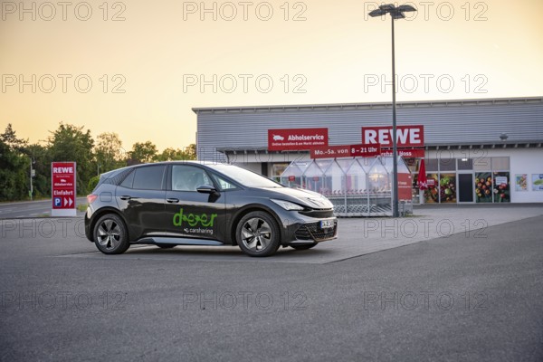 Car parked in a parking lot in front of a supermarket in the evening light, Deer e-car sharing,