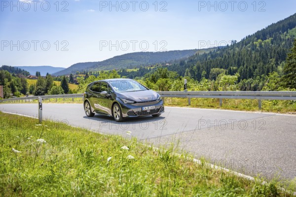 Car driving on a winding road in a mountainous landscape, Deer E-car sharing, Cupra electric car,