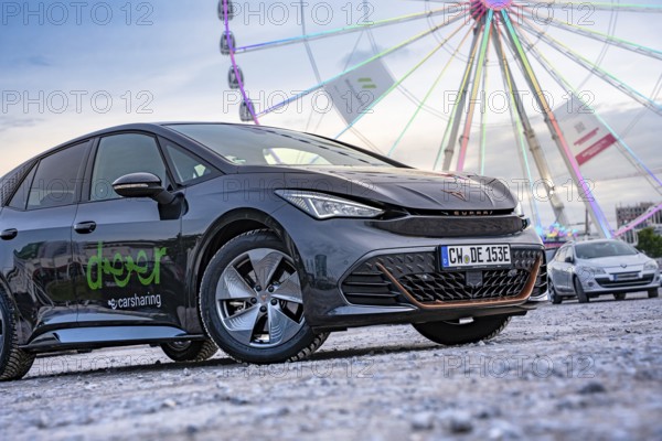 Modern cars in front of a big Ferris wheel at a trade show, Deer E-Car Sharing, Cupra electric car,