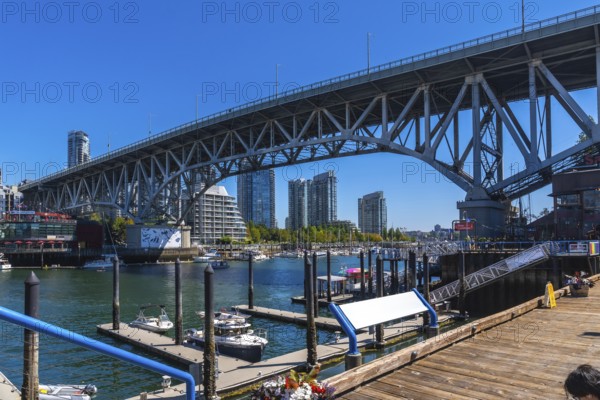 Granville street bridge dominating the skyline over false creek with boats moored at the marina and