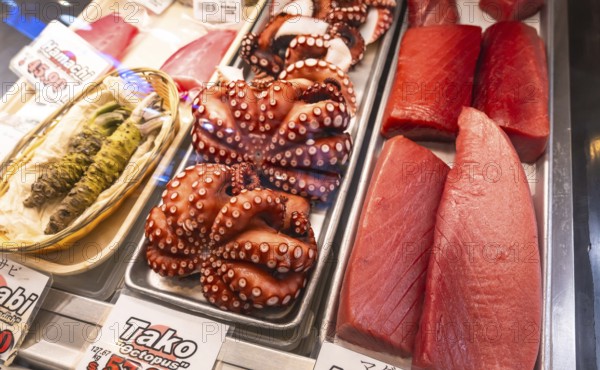 Fresh octopus and tuna fillets are displayed on ice alongside wasabi at a fish market in vancouver,