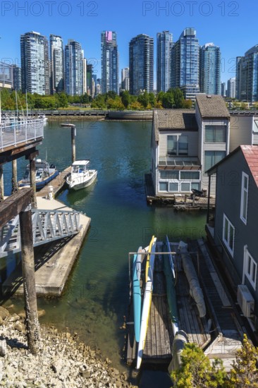 Kayaks resting on a wooden dock near floating homes, with a motorboat moored nearby and the