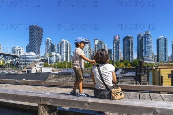 Sitting on a wooden bench at granville island market, a mother and son admire the stunning