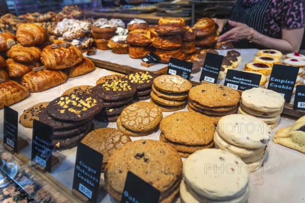 Freshly baked cookies and pastries are neatly arranged and labeled with prices in a bakery display